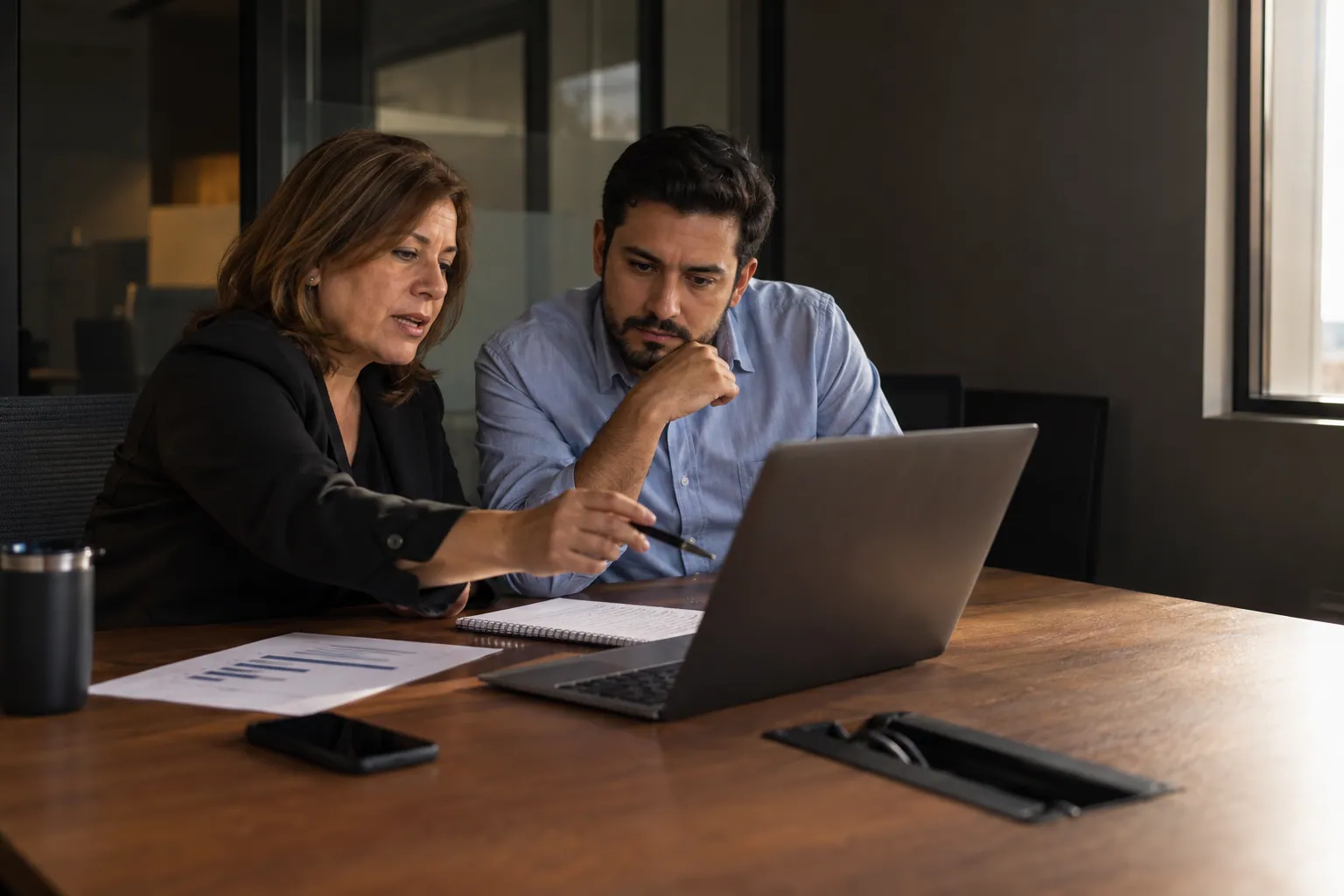 Una gerente revisa con un líder de equipo el avance de capacitación en una laptop.